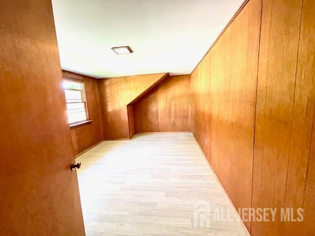 hallway with wooden walls and light hardwood / wood-style flooring