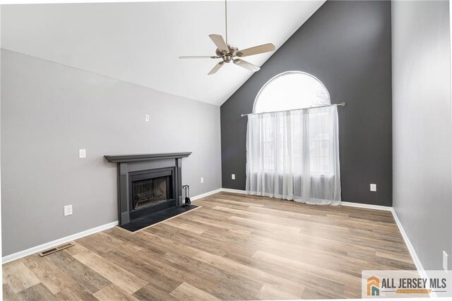 unfurnished living room with ceiling fan, high vaulted ceiling, and light wood-type flooring