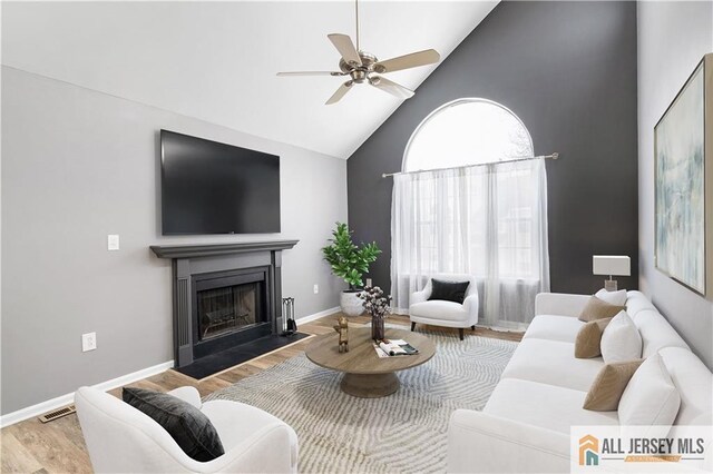 living room featuring high vaulted ceiling, hardwood / wood-style floors, and ceiling fan