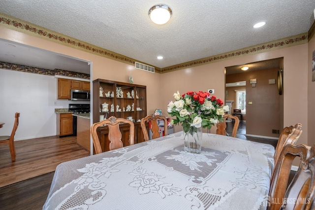 dining room featuring visible vents, a textured ceiling, and dark wood finished floors