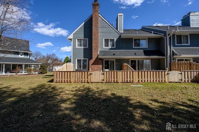 back of property with a gate, fence, a chimney, and a lawn