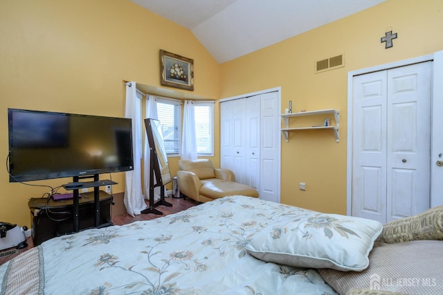 bedroom with vaulted ceiling, multiple closets, and visible vents