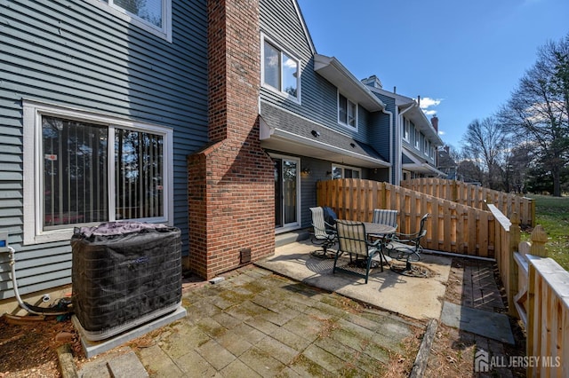 view of patio featuring central AC, fence, and outdoor dining area