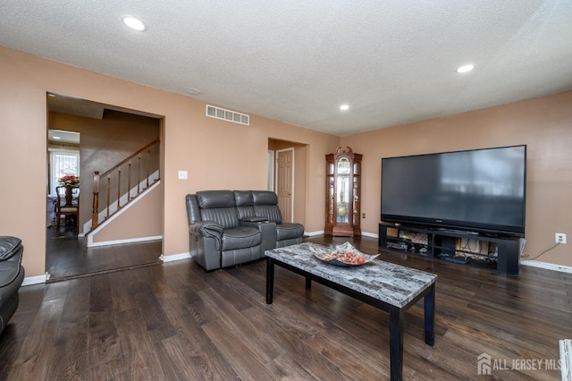 living room featuring wood finished floors, visible vents, a textured ceiling, and stairway