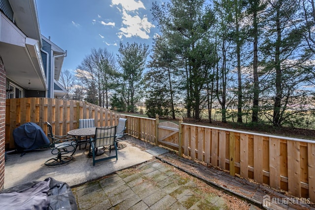 view of patio / terrace with grilling area, a fenced backyard, outdoor dining area, and a gate