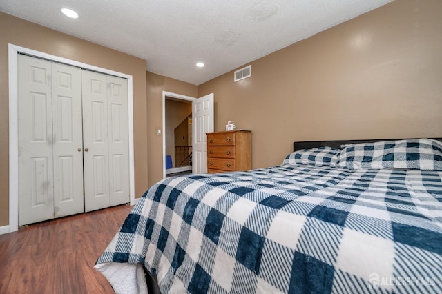 bedroom with a textured ceiling, visible vents, recessed lighting, wood finished floors, and a closet