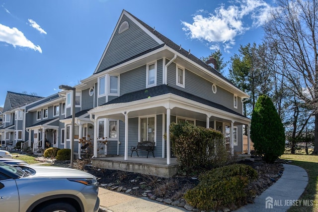 view of front facade featuring a chimney and covered porch