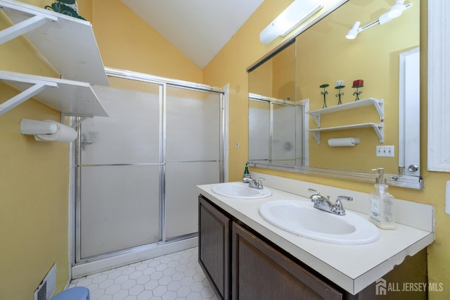 full bath with lofted ceiling, a shower with shower door, a sink, and visible vents