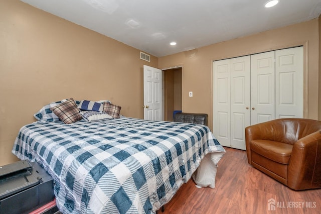bedroom featuring recessed lighting, wood finished floors, visible vents, and a closet