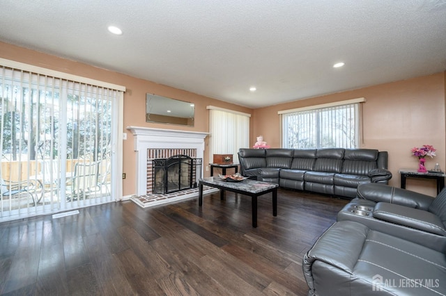living area featuring a textured ceiling, baseboards, recessed lighting, wood finished floors, and a fireplace