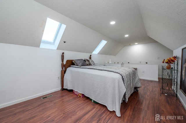 bedroom with visible vents, baseboards, vaulted ceiling with skylight, a textured ceiling, and dark wood-style flooring