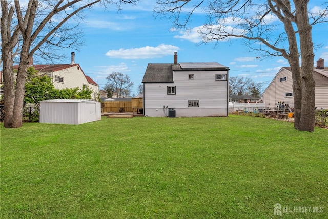 273 Park St, Franklin Twsp, NJ 08873 - rear view of property featuring a shed, an outbuilding, a shingled roof, central AC unit, and a chimney
