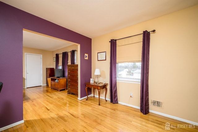 empty room featuring light wood finished floors, visible vents, and baseboards