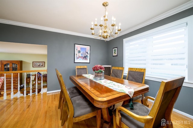 dining space with a notable chandelier, baseboards, light wood-type flooring, and ornamental molding