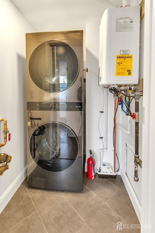 clothes washing area with stacked washer and dryer, laundry area, baseboards, and tile patterned floors