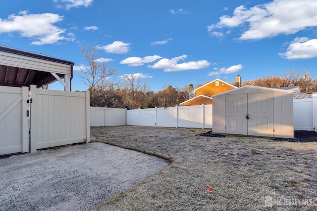 view of yard featuring a storage shed, a gate, a patio area, a fenced backyard, and an outdoor structure