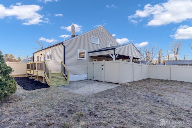 back of property featuring a deck, a fenced backyard, and a gate