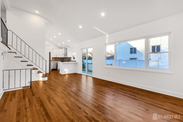 unfurnished living room featuring lofted ceiling, stairway, wood finished floors, and baseboards