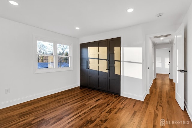 unfurnished bedroom featuring dark wood-type flooring, recessed lighting, a closet, and baseboards