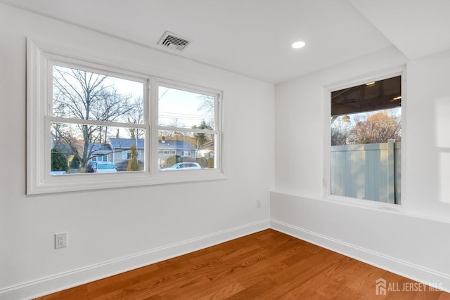 spare room with baseboards, visible vents, wood finished floors, and recessed lighting