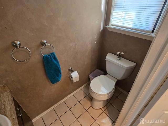 bathroom featuring baseboards, tile patterned flooring, and toilet