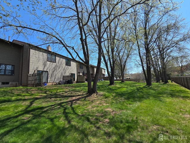 view of yard with central air condition unit and fence