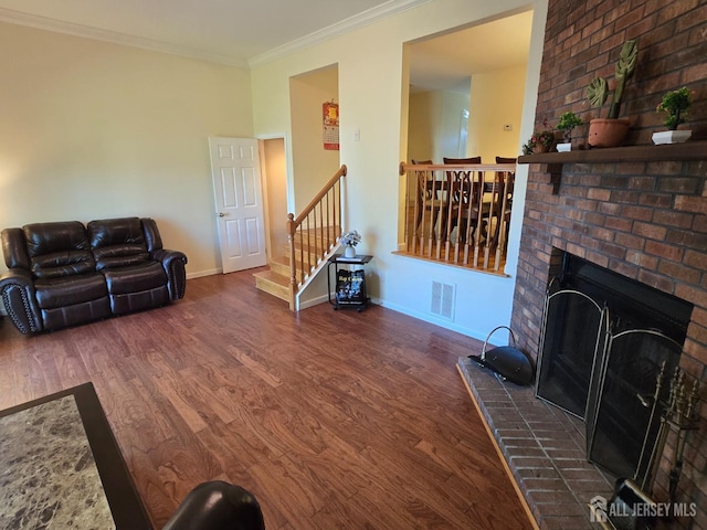 living area with visible vents, crown molding, a brick fireplace, wood finished floors, and baseboards