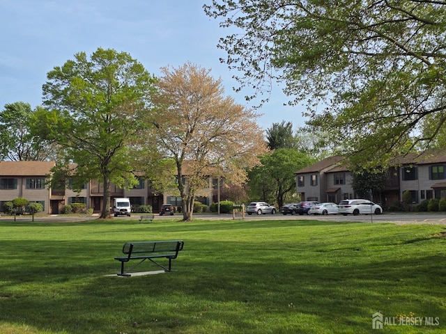 view of home's community featuring a lawn and uncovered parking