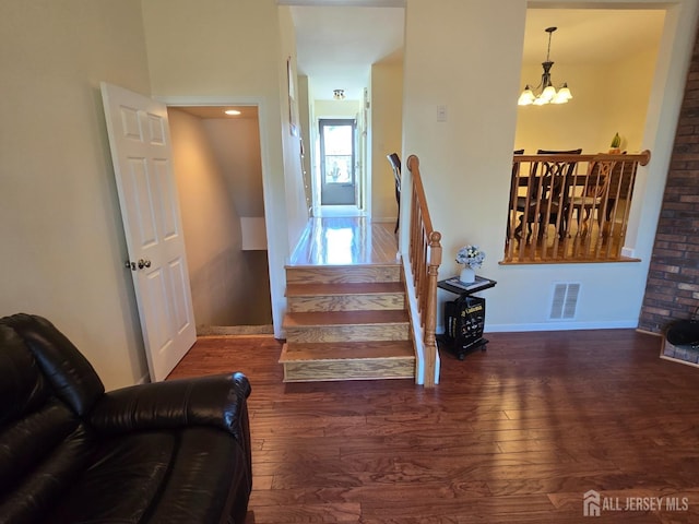 staircase featuring baseboards, visible vents, an inviting chandelier, and wood finished floors