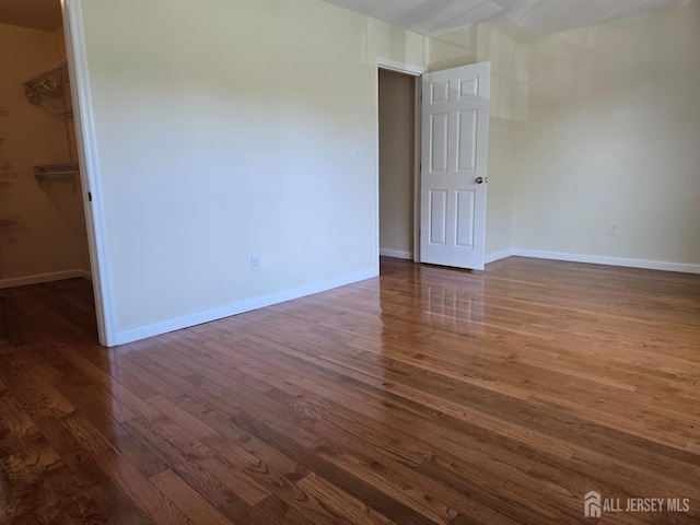 unfurnished room featuring baseboards and dark wood-style flooring