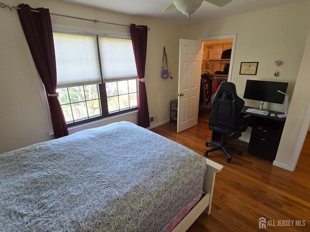 bedroom with visible vents, a closet, wood finished floors, baseboards, and a spacious closet
