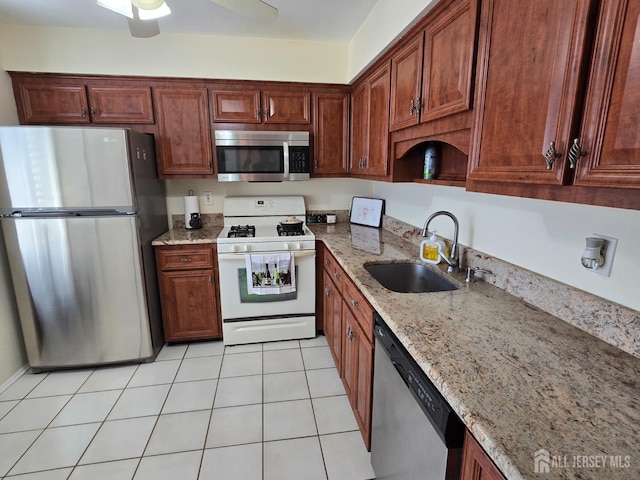 kitchen with ceiling fan, appliances with stainless steel finishes, light stone countertops, a sink, and light tile patterned floors