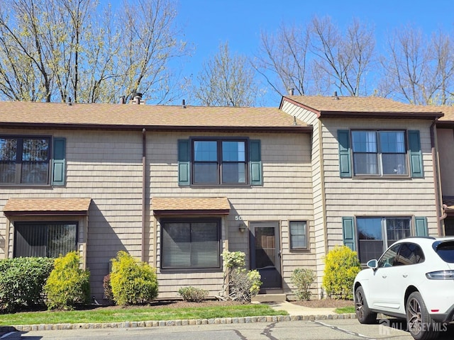 multi unit property with roof with shingles and a chimney