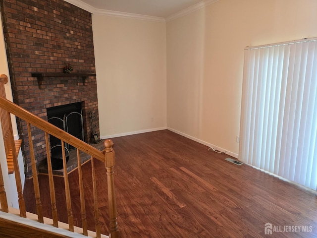 unfurnished living room with visible vents, ornamental molding, wood finished floors, baseboards, and stairway