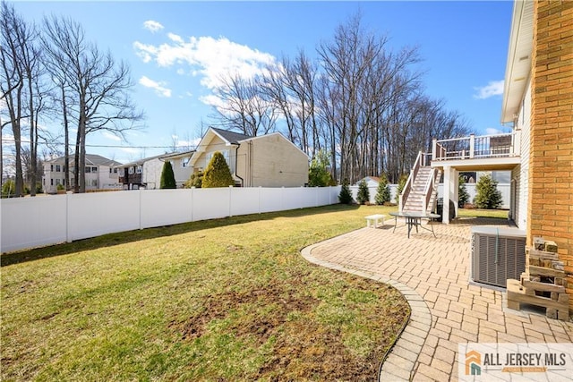 view of yard with a patio area, central AC unit, stairs, and fence