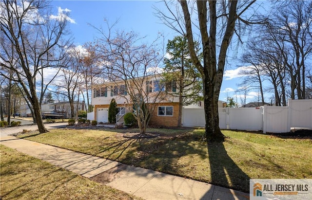 view of front facade featuring a gate, fence, concrete driveway, a front yard, and brick siding