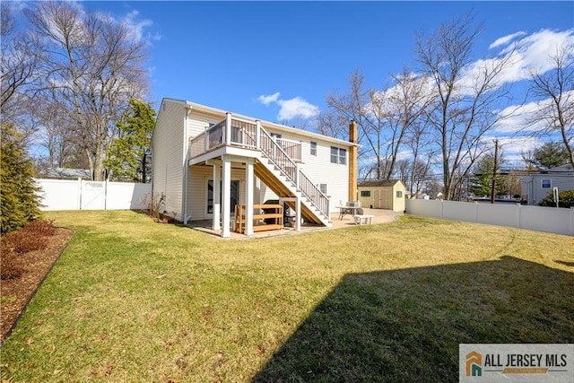 back of property featuring a fenced backyard, stairs, an outdoor structure, a storage shed, and a patio area