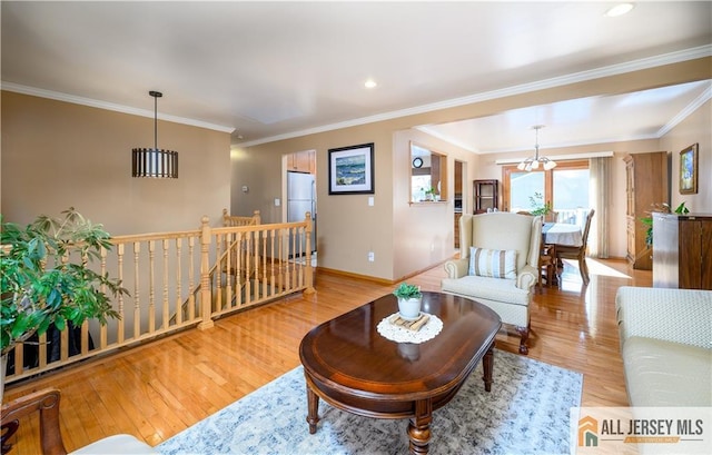 living room with wood finished floors, baseboards, recessed lighting, crown molding, and a chandelier