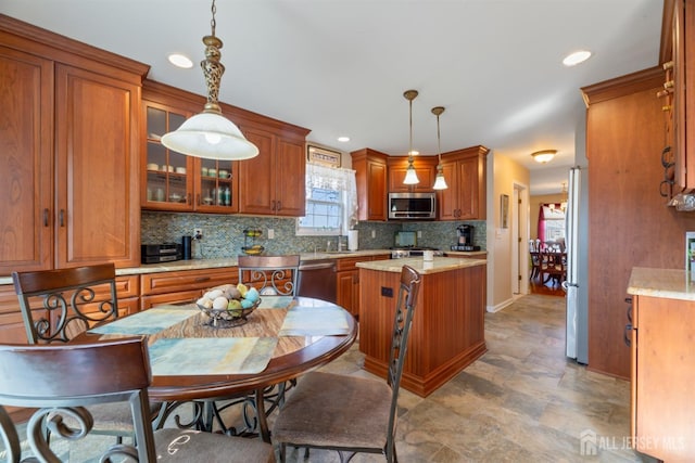 kitchen with glass insert cabinets, brown cabinetry, tasteful backsplash, and stainless steel appliances