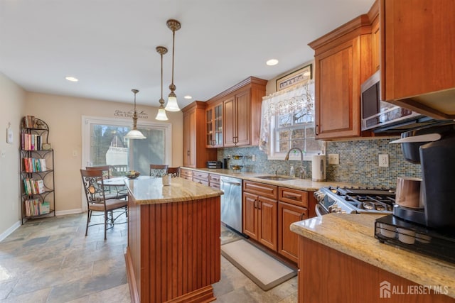 kitchen featuring a sink, light stone counters, backsplash, stainless steel appliances, and brown cabinetry