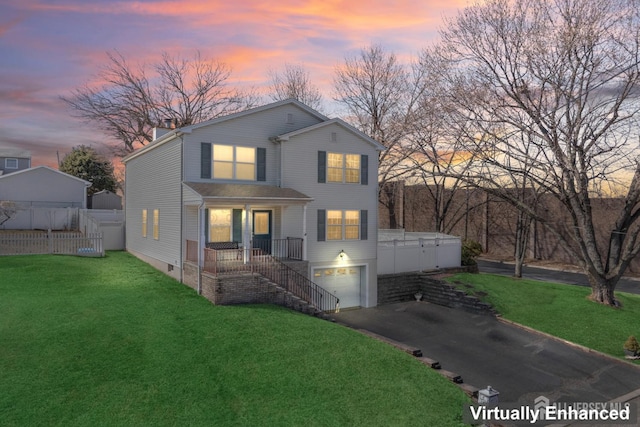 traditional home featuring stairway, fence, driveway, an attached garage, and a yard