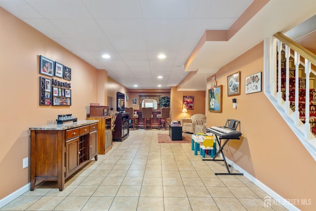 interior space featuring light tile patterned floors, a drop ceiling, recessed lighting, and baseboards