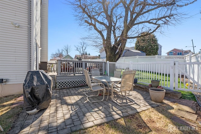 view of patio featuring a wooden deck, a fenced backyard, outdoor dining space, and grilling area