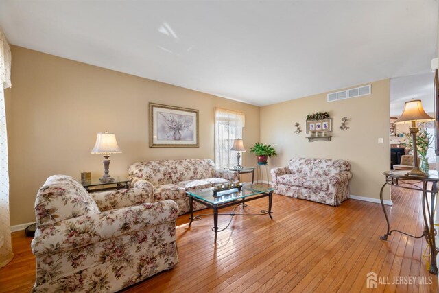 living area featuring visible vents, baseboards, and wood-type flooring