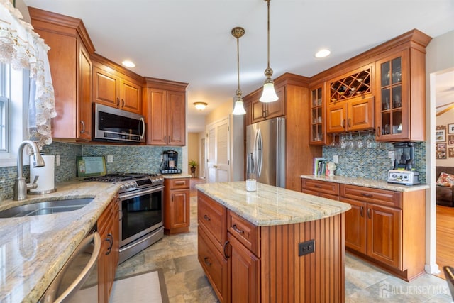 kitchen featuring brown cabinets, a sink, light stone counters, tasteful backsplash, and appliances with stainless steel finishes