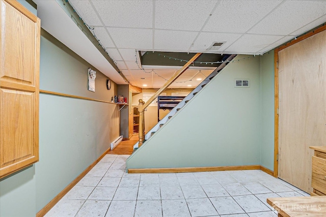 1332 Crescent Ave, Roselle, NJ 07203 - finished below grade area with baseboard heating, a paneled ceiling, stairway, baseboards, and light tile patterned floors