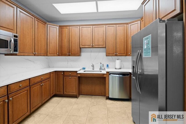 kitchen with tasteful backsplash, stainless steel appliances, light stone countertops, and sink