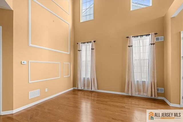 unfurnished room with hardwood / wood-style floors and a high ceiling