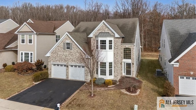 front of property with a garage, central AC, and a front yard