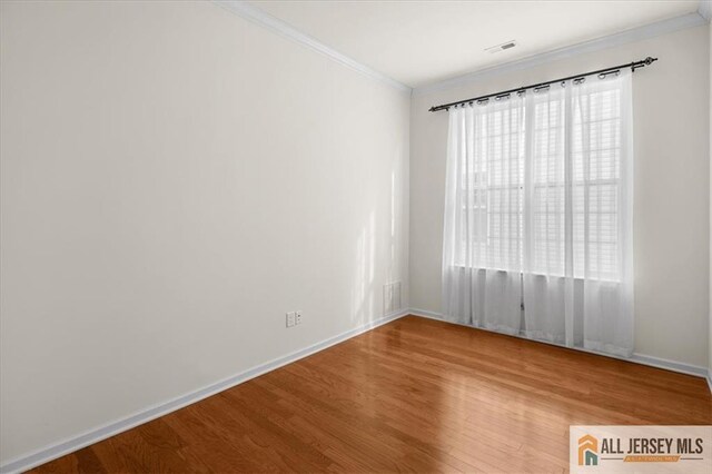 spare room with ornamental molding and hardwood / wood-style floors